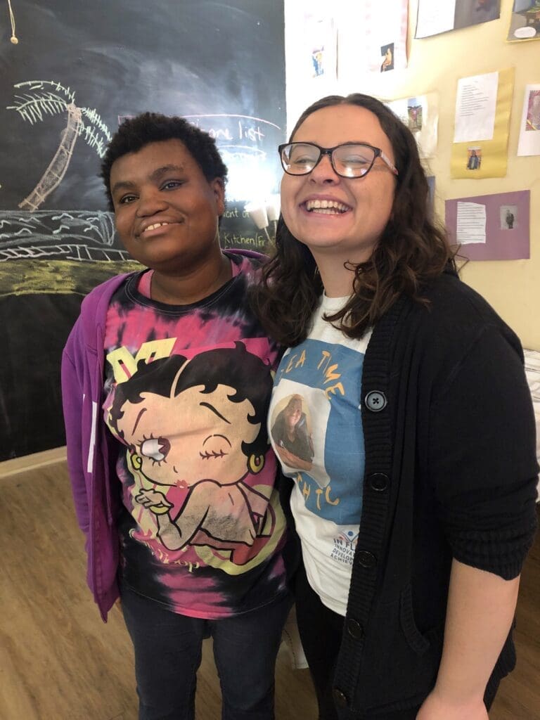 Two friends smiling together in a casual setting.