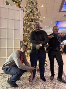 Three men posing by decorated Christmas tree
