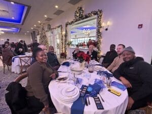 Group seated at festive table with Christmas tree