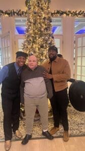 Three people posing by decorated Christmas tree