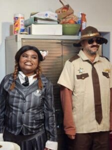 Two people dressed in costumes, one as a police officer and the other in a gray suit.